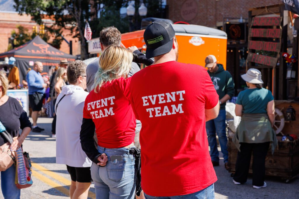 An image of two volunteers wearing red shirts that say "event staff" on the back at Harvest Moon Celebration in Ogden, Utah.